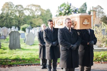 men helping to carry or a coffin at a funeral.